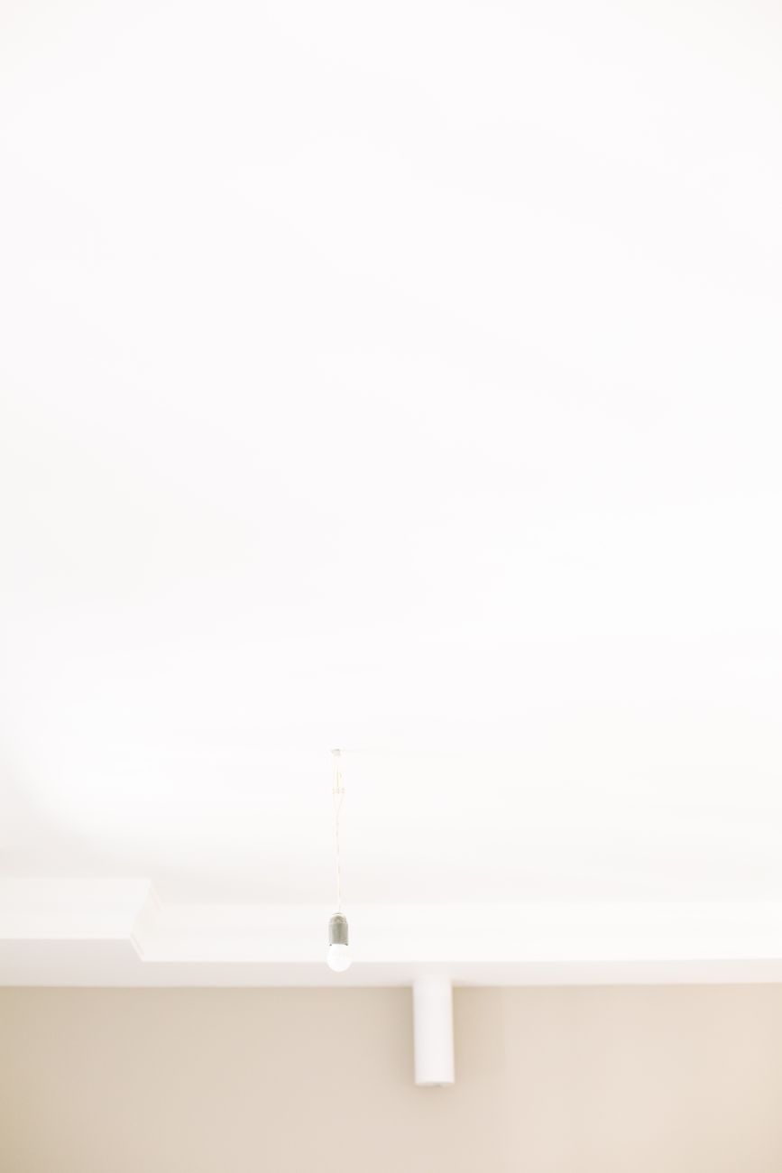 Simple minimalist ceiling design with a hanging light bulb, creating a serene atmosphere.