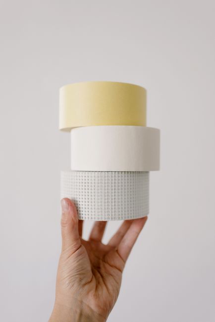 Crop unrecognizable person demonstrating various masking tapes for repair against white background at home